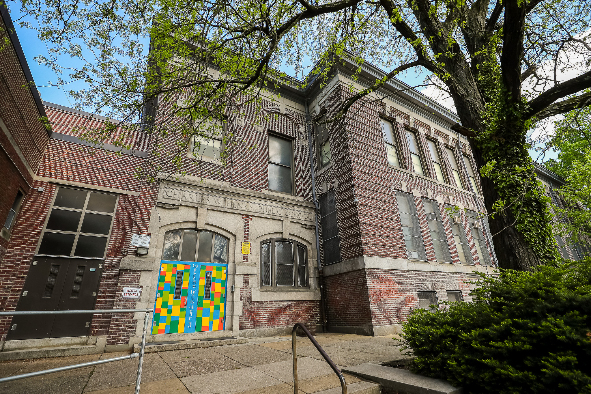 Exterior of Charles W. Henry School with the main entrance and historic brick building surrounded by trees.